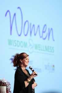 Kelly Swanson  with microphone being funny women's health weight loss, womens speakers, speak well being 